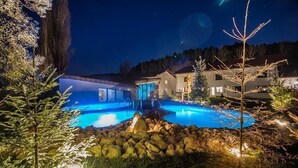 A nighttime view of a residential area with a swimming pool, surrounded by trees and houses. - Wolkendorf Bio Hotel & Spa (Vulcan)