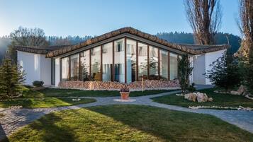 Una casa moderna con base de piedra, grandes ventanales y techo de la misma material.