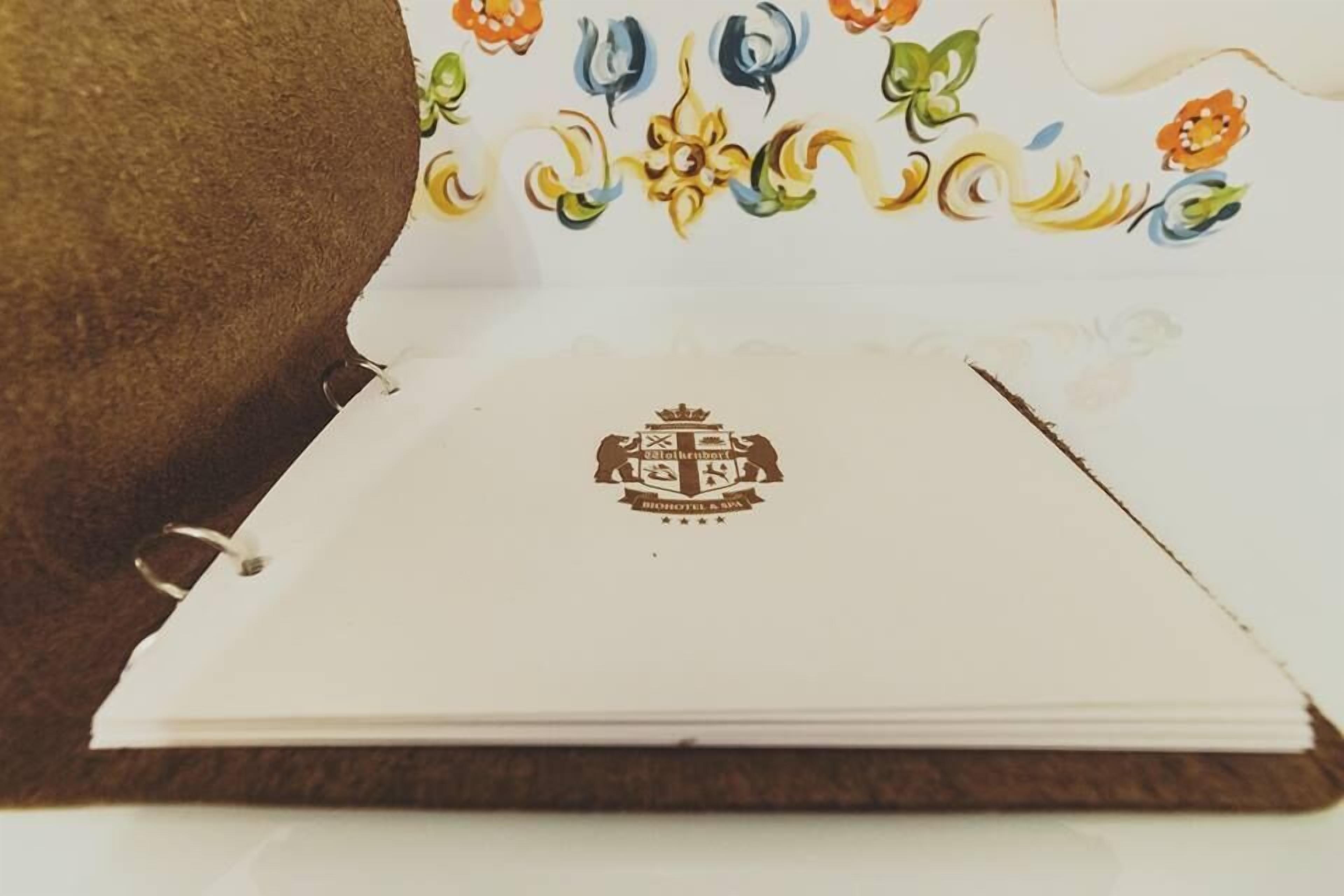 A closed book with a white cover featuring a colorful floral design and a central emblem.