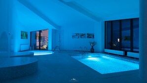 A modern bathroom with a large bathtub, a shower, and a small pool area. - Wolkendorf Bio Hotel & Spa (Vulcan)