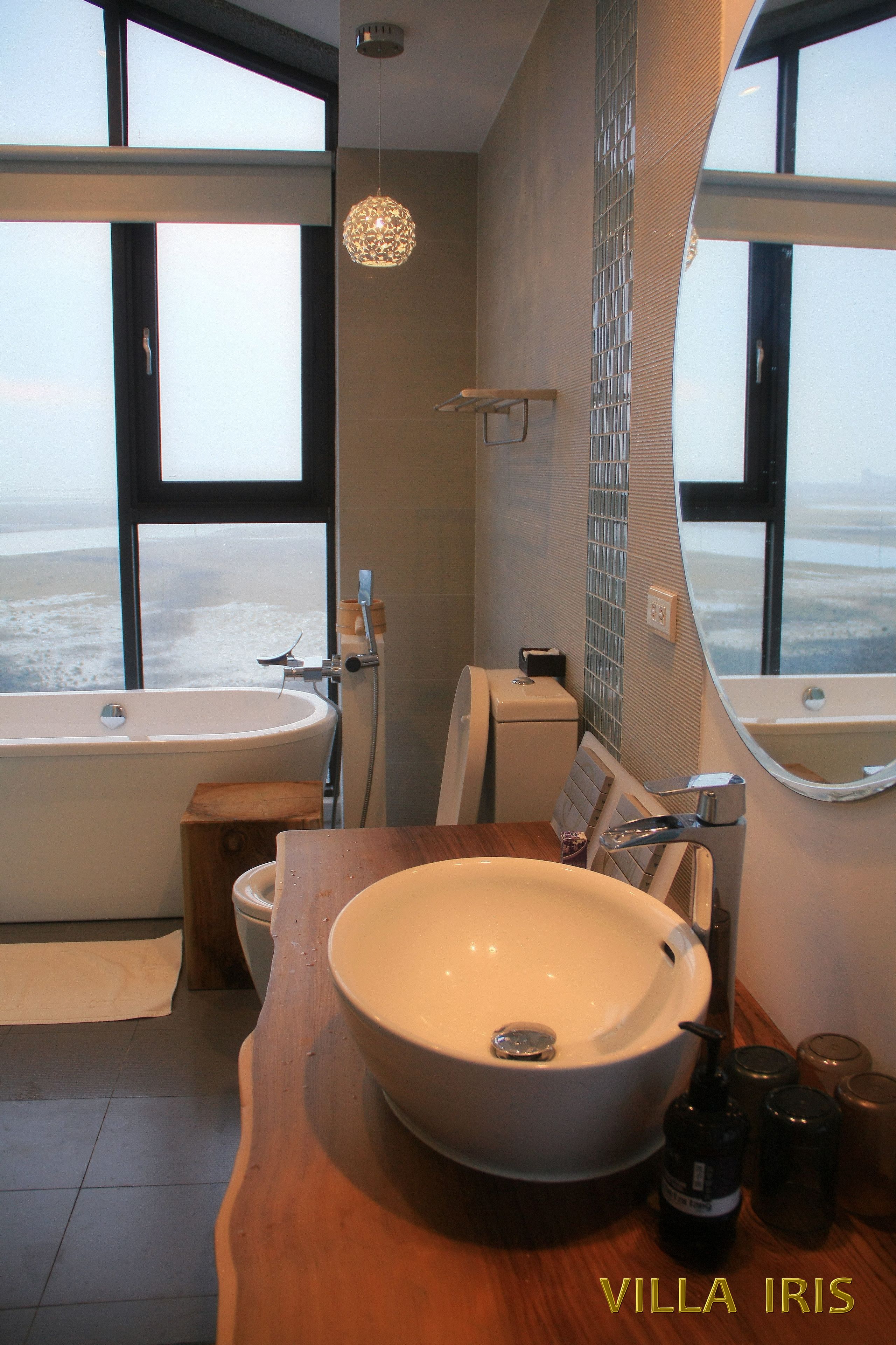 A bathroom with a large bathtub, a sink, and a mirror.