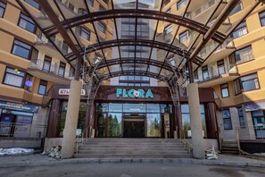 A building entrance with a sign reading "FLORA" and a staircase leading up to it.