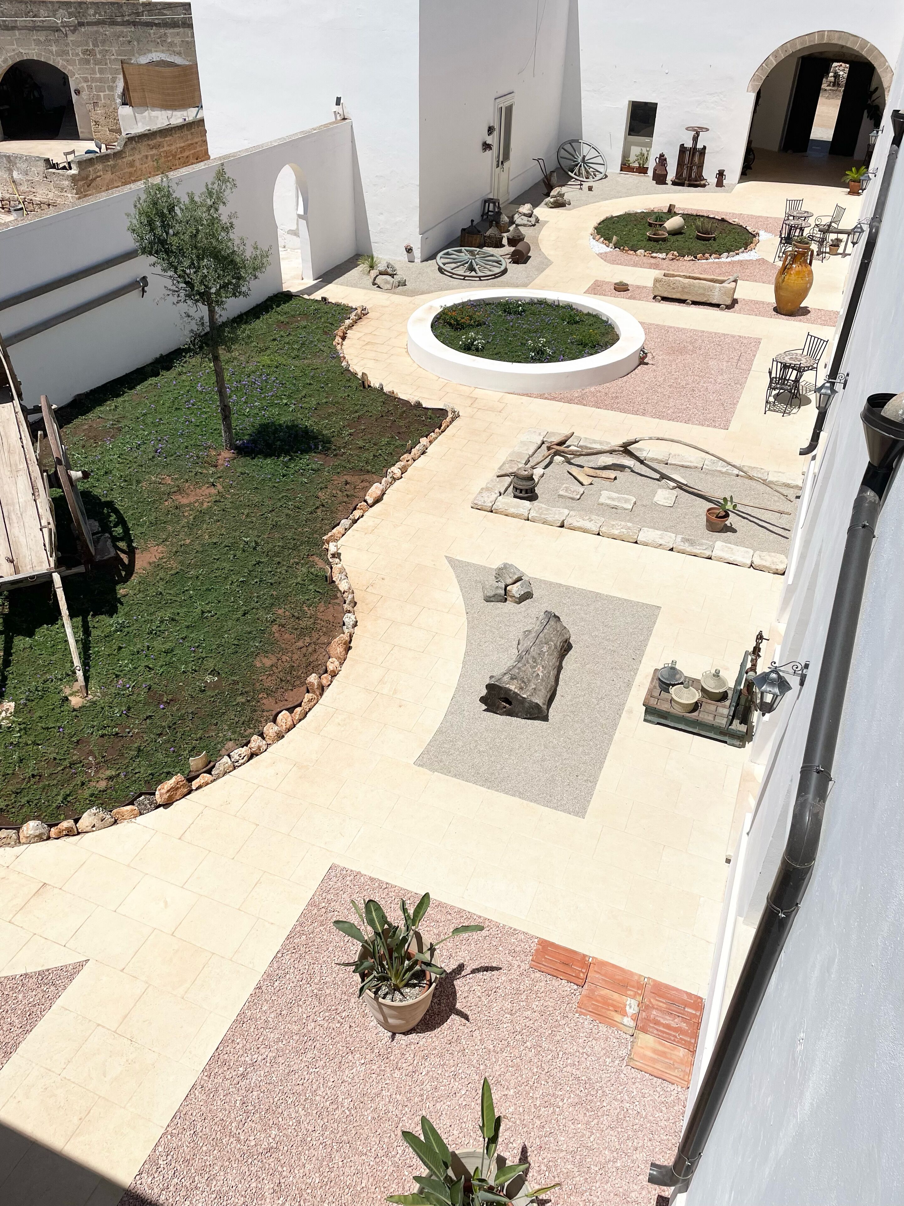 A courtyard with a paved walkway, a small garden area, and outdoor furniture.