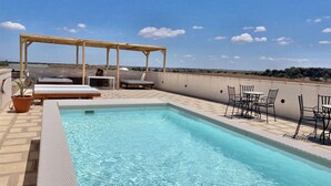 A rooftop pool with lounge chairs and a pergola, surrounded by a clear blue sky. - Masseria Vico (Nardò)