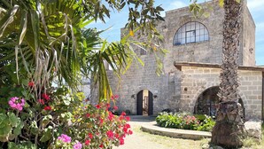 A historic stone building with a large arched window and a gravel pathway. - Masseria Vico (Nardò)