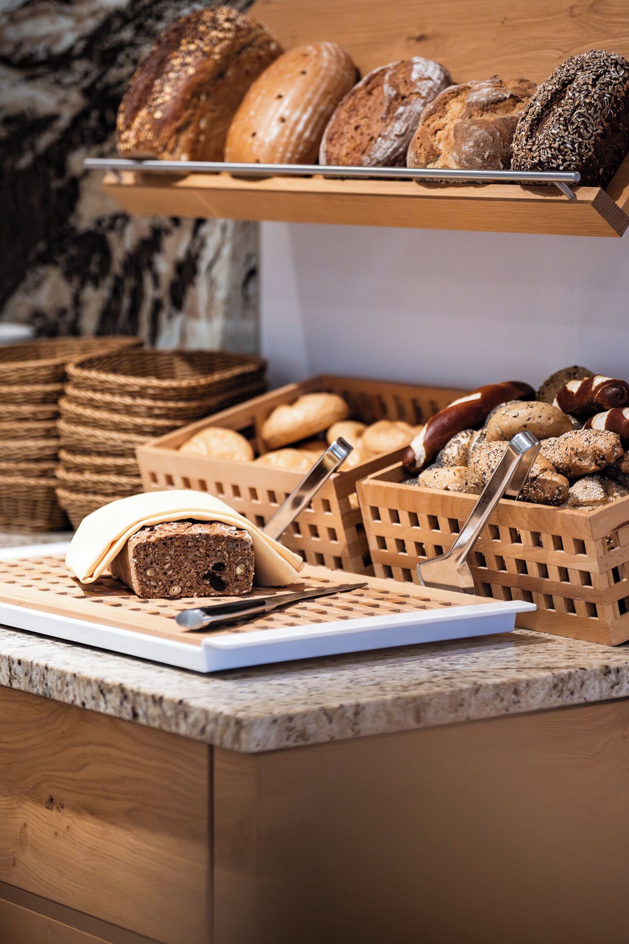 A bakery display with various breads and pastries on a wooden counter.