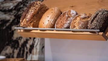 A bakery display with various breads and pastries on a wooden counter.