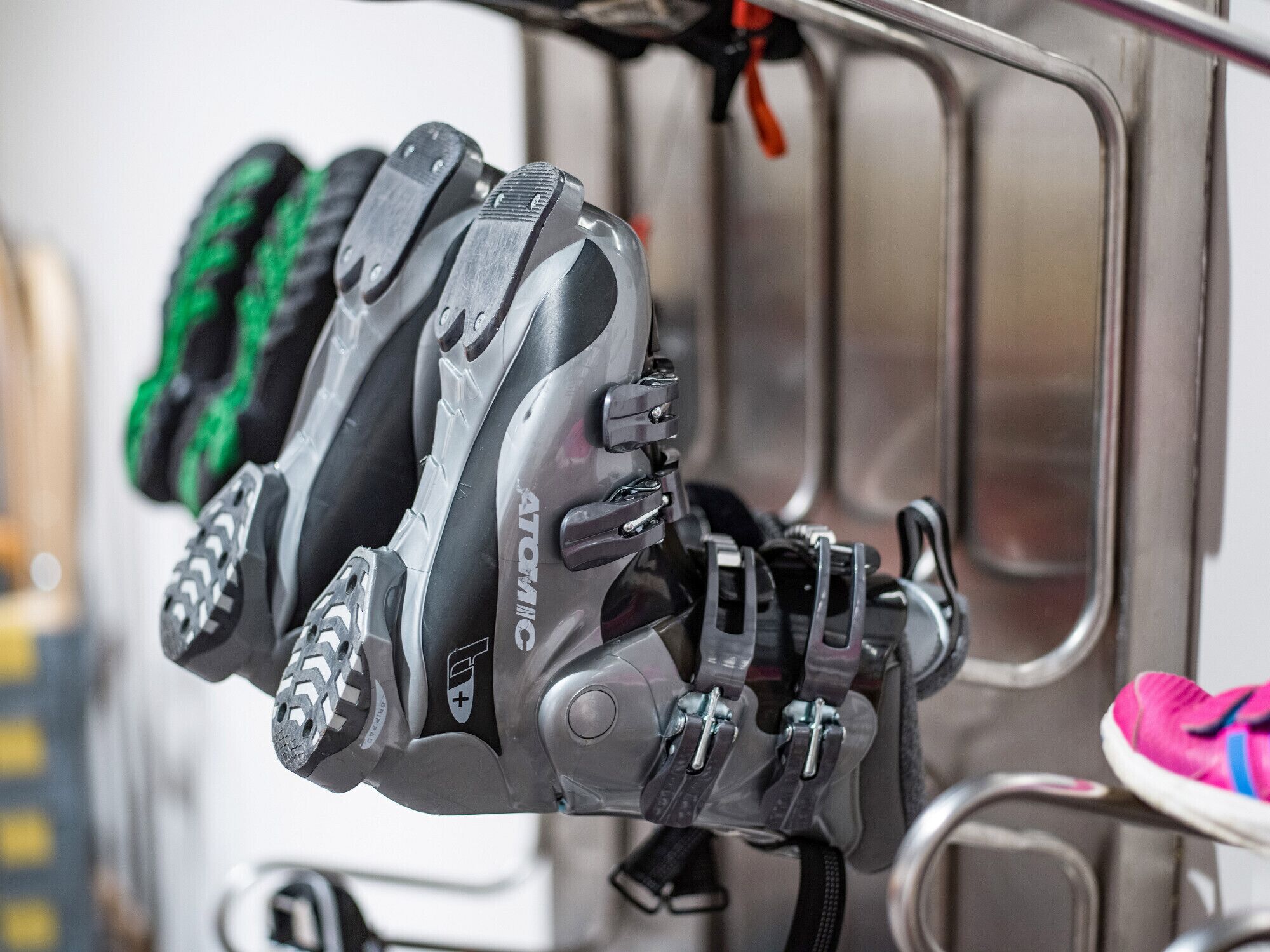 A row of roller skates hanging on a metal rack.