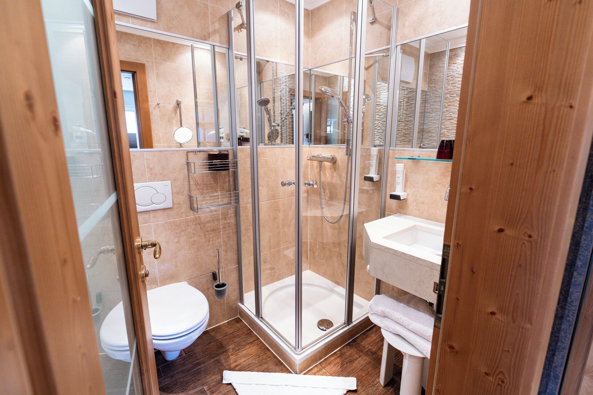 Ein modernes Badezimmer mit einer gläsernen Duschkabine, einer weißen Toilette und einem Waschbecken mit Spiegel.