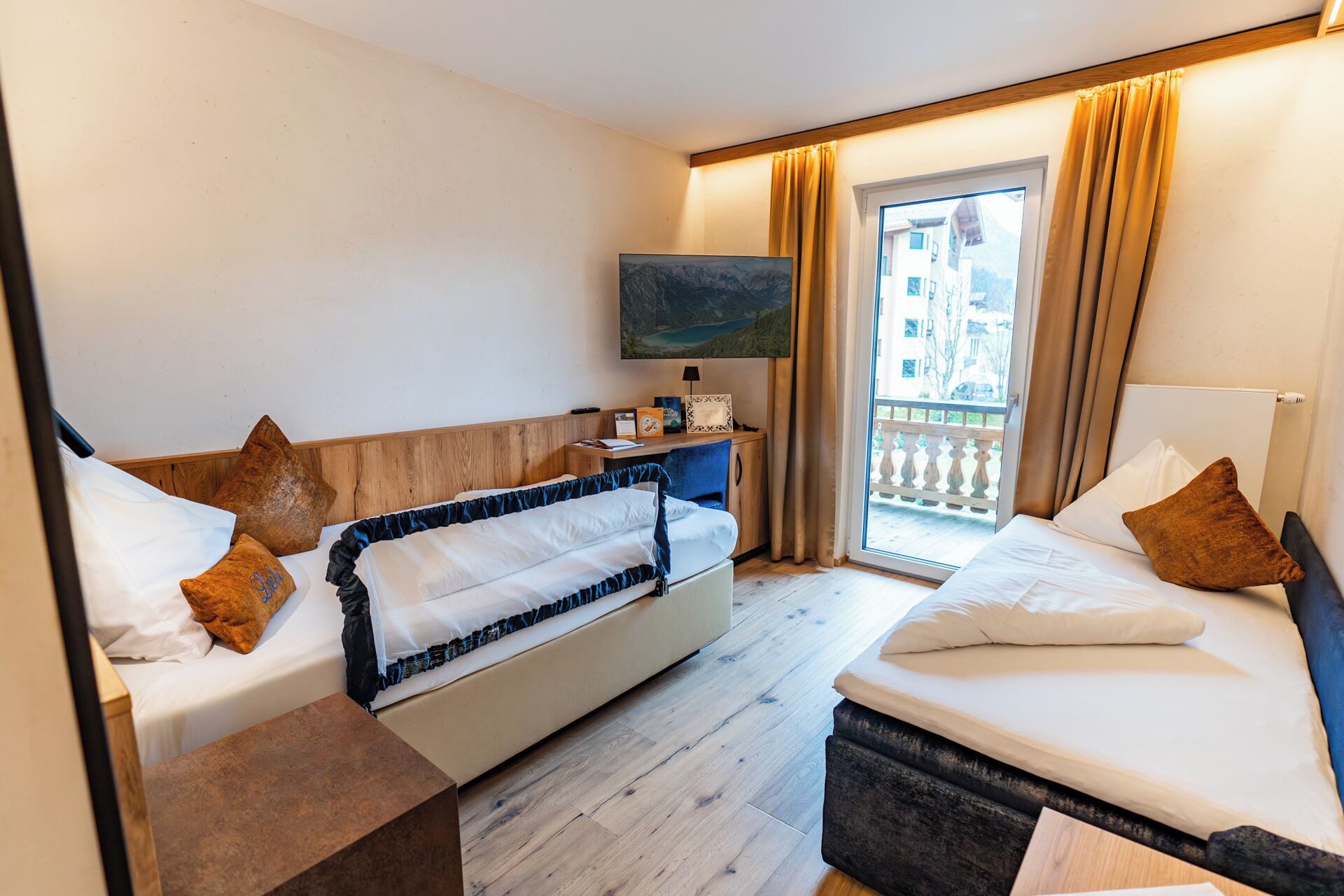 Quarto de hotel com duas camas, televisão, varanda e um quadro na parede.