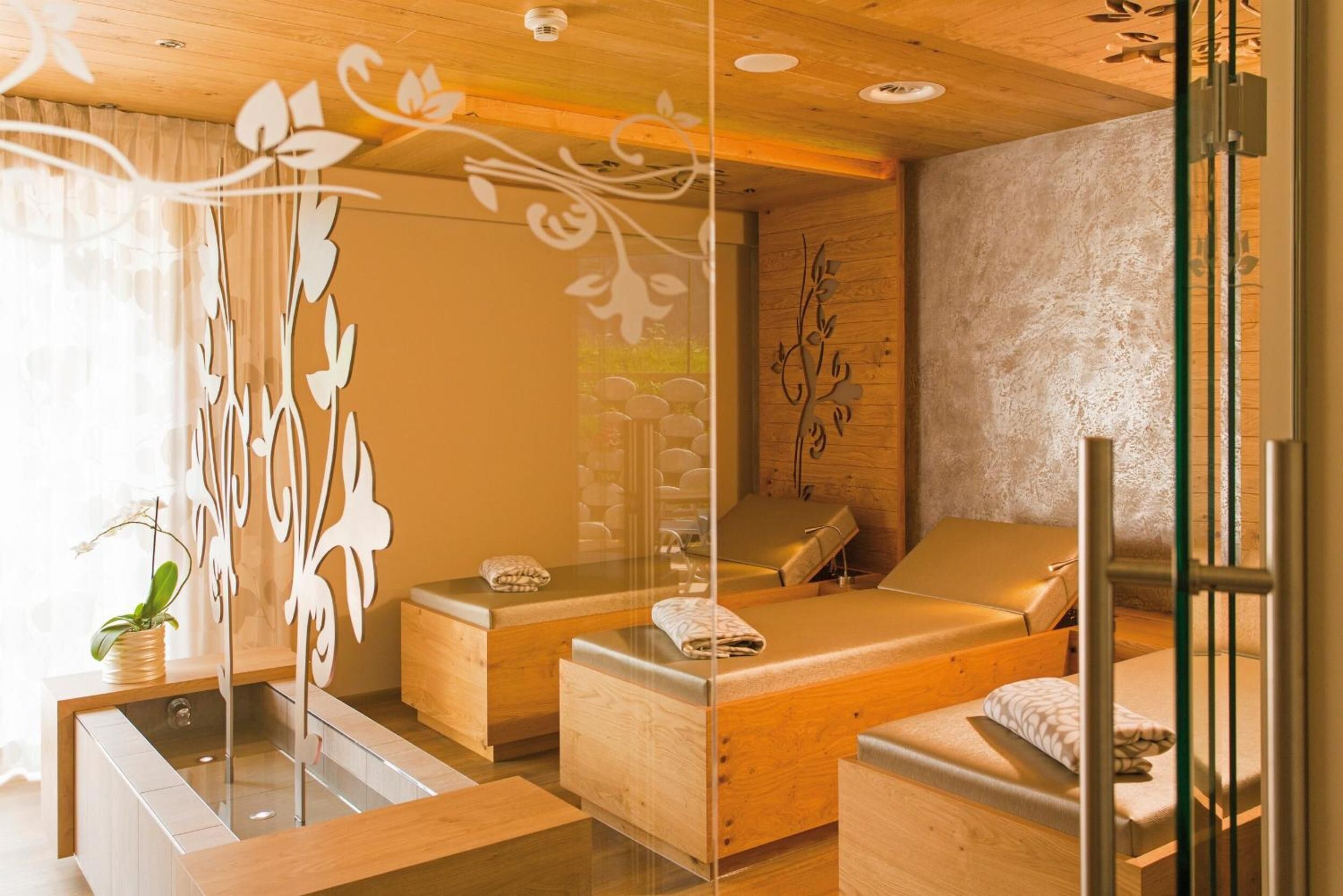 A spa room with wooden furniture, a glass partition, and decorative wall art.
