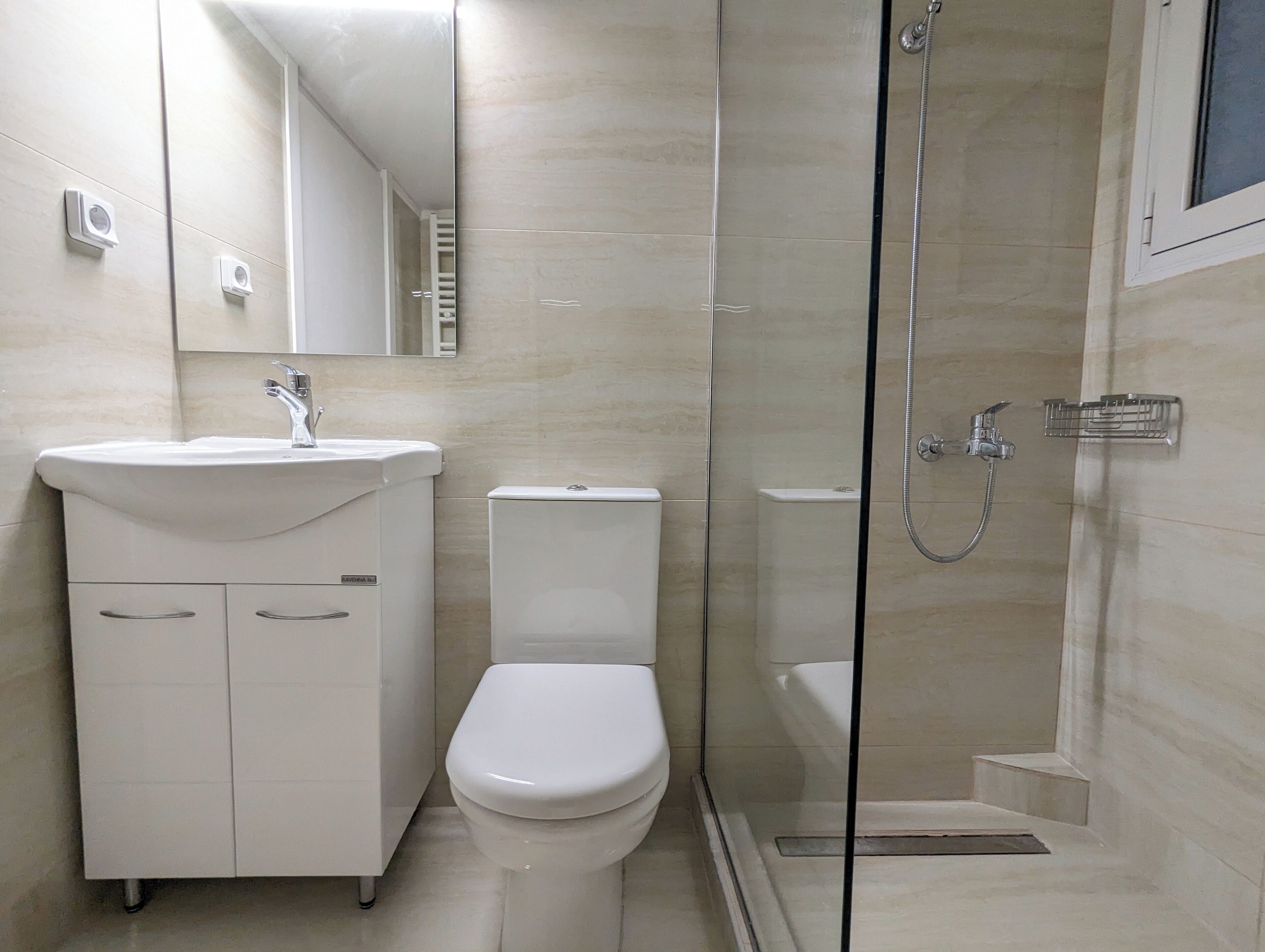 A modern bathroom with a white sink, toilet, and glass-enclosed shower.