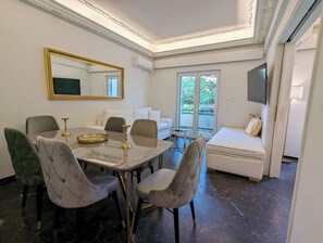 A dining area with a marble table, cushioned chairs, a gold-framed mirror, and a sofa with a patterned cushion. - Acropolis View Dream Apartments (Athens)