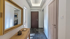Um corredor com um banco de madeira, um espelho grande e uma porta no final.