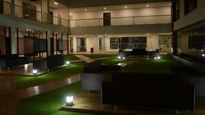 A spacious indoor area with multiple seating arrangements, a central open space, and a balcony overlooking the interior. - The Divine Resort (Veraval)