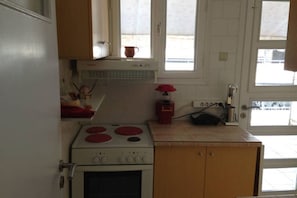 A kitchen with a stove, oven, and a window above the counter.