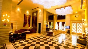 A hotel lobby with a checkered floor, a reception desk, seating area, and a large chandelier. - Stardom Resort (Jaipur)