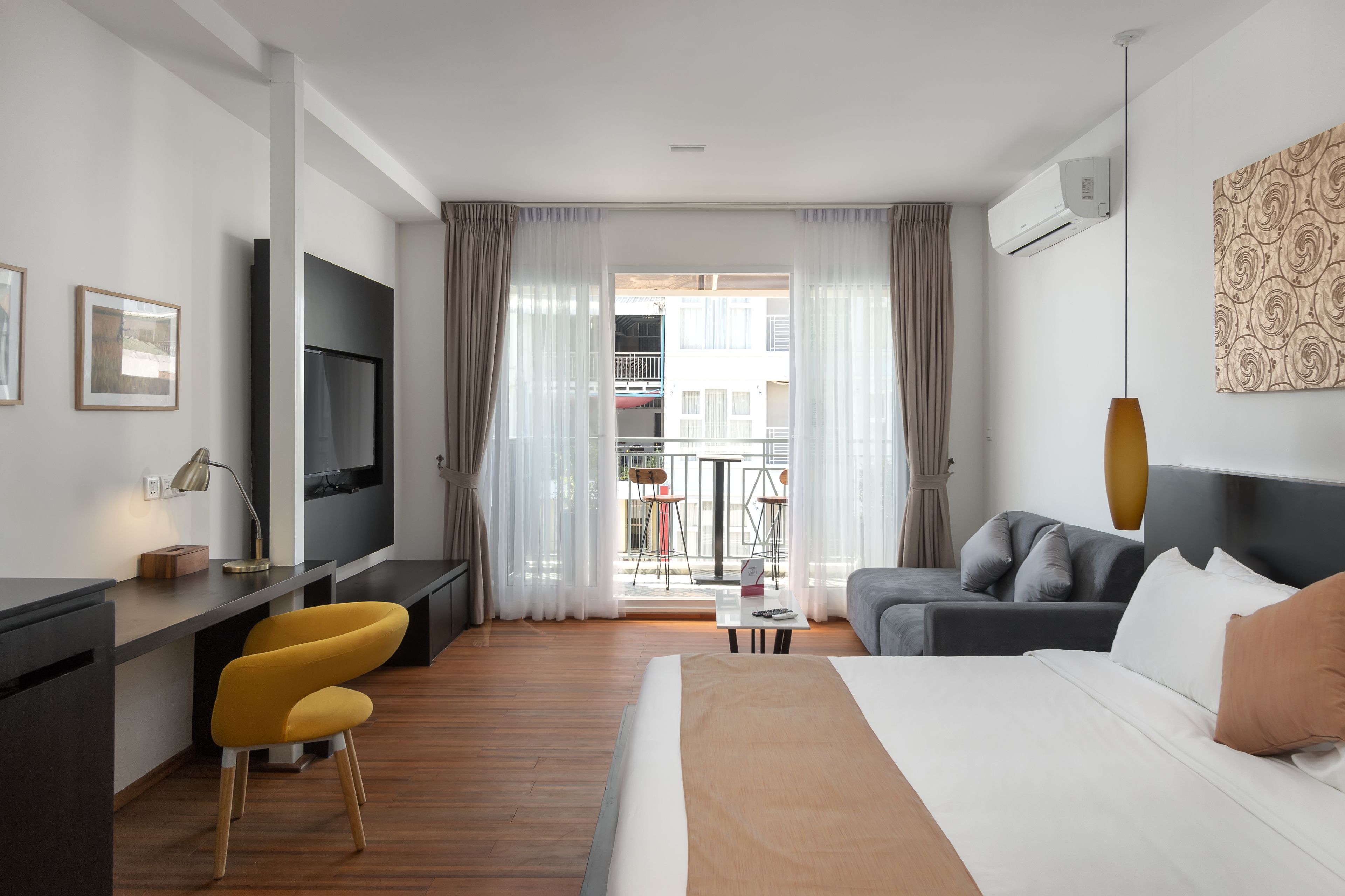 A modern hotel room with a bed, a desk, a TV, and a sofa.