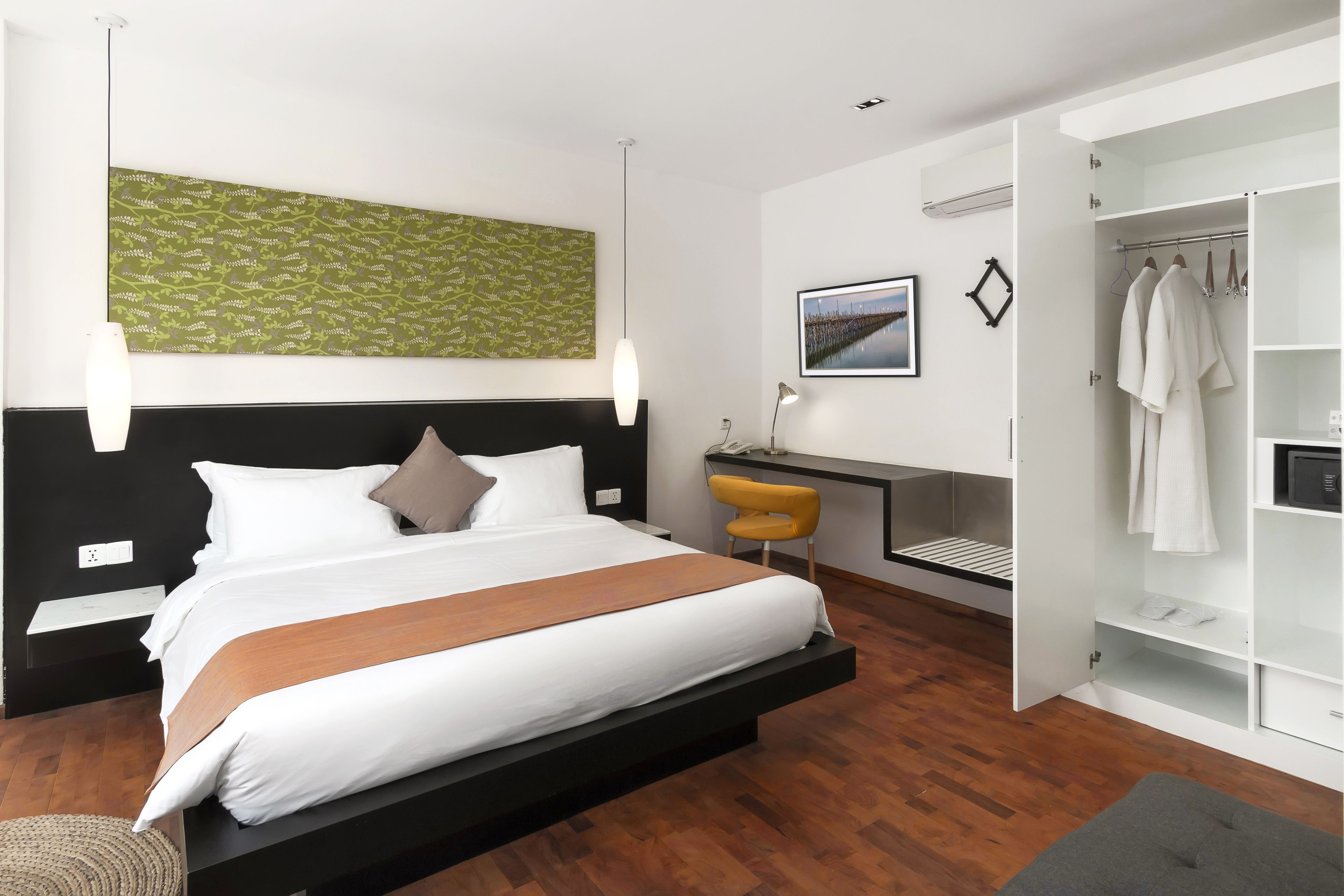 A modern bedroom with a large bed, a desk, and a walk-in closet.