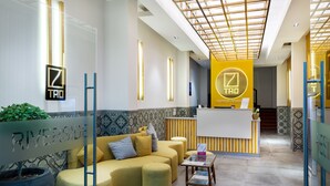 A modern hotel lobby with a reception desk, seating area, and a glass partition with the word "RIVERSIDE". - Tao Riverside Residence (Phnom Penh)