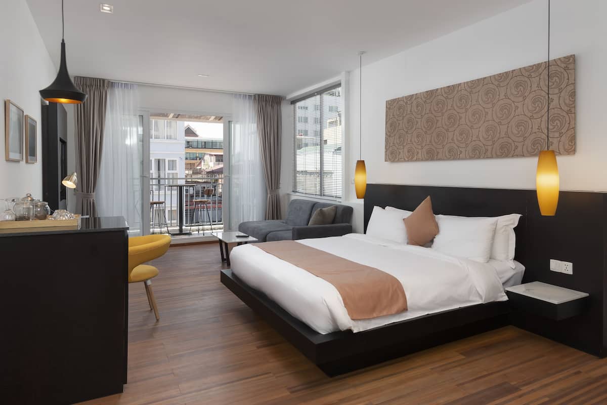 Moderni hotellihuone, jossa on suuri sänky, työpöytä ja sohva.