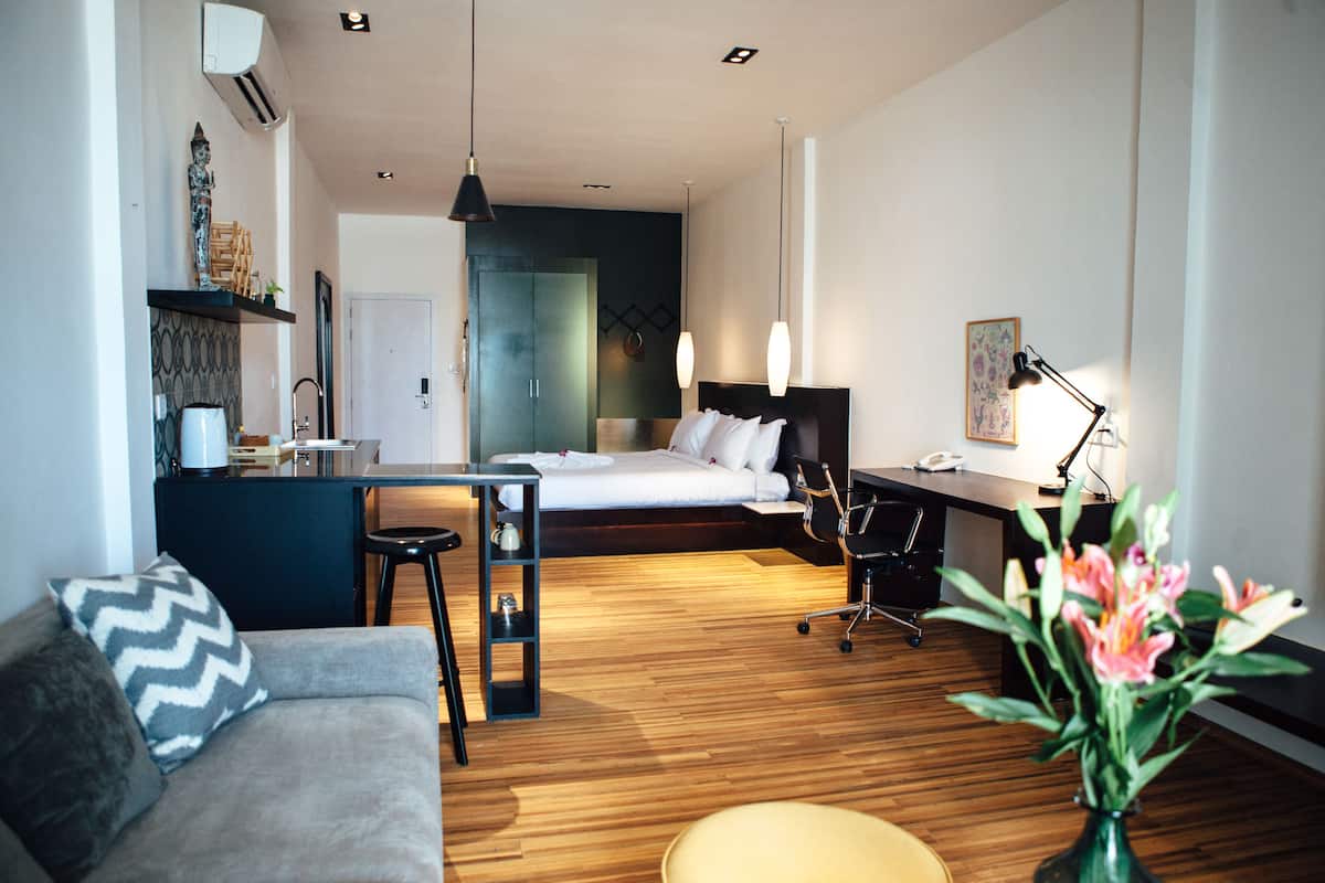 Moderni hotellihuone, jossa on sänky, työpöytä ja oleskelualue.