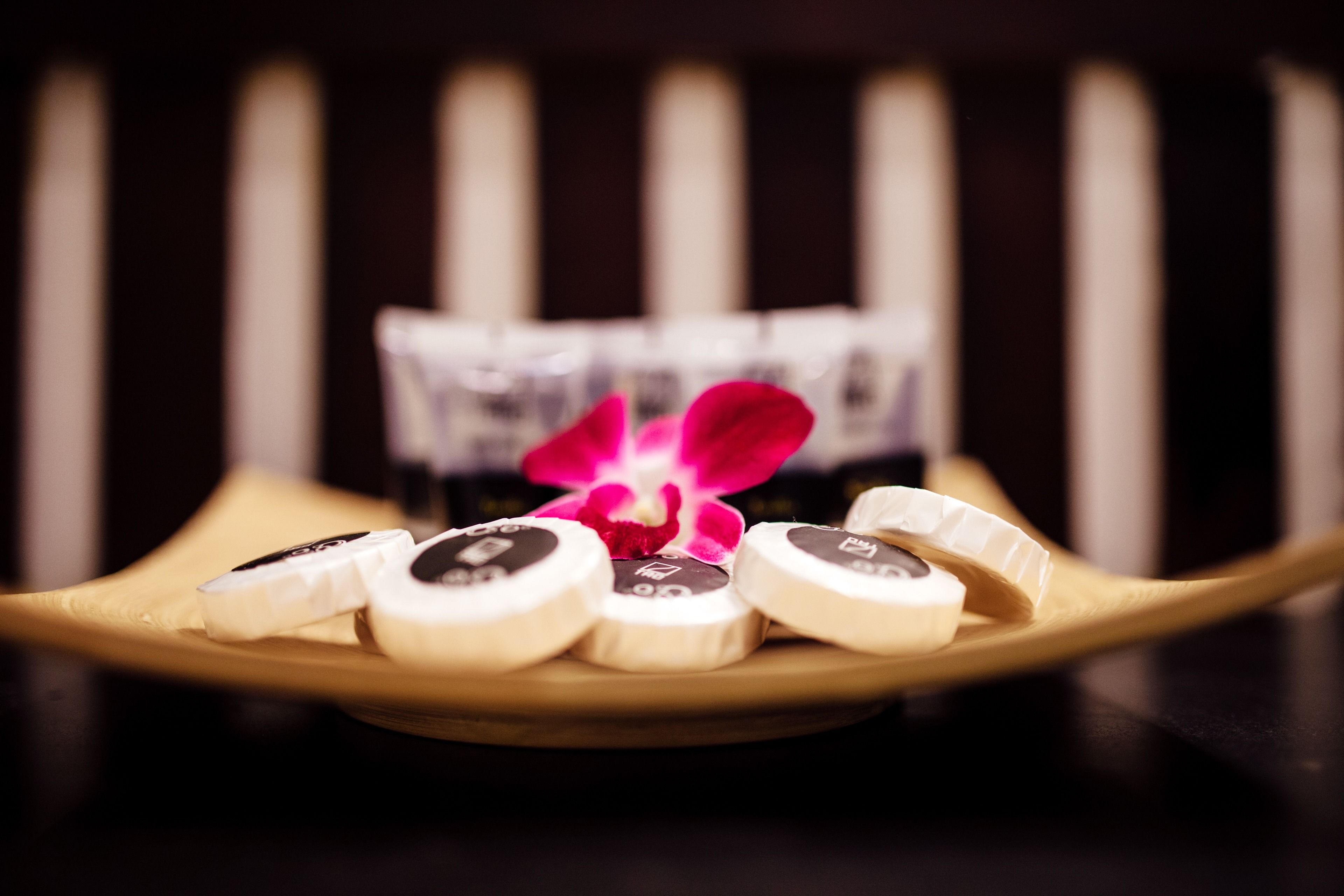 A plate with several chocolate-covered items and a pink orchid.