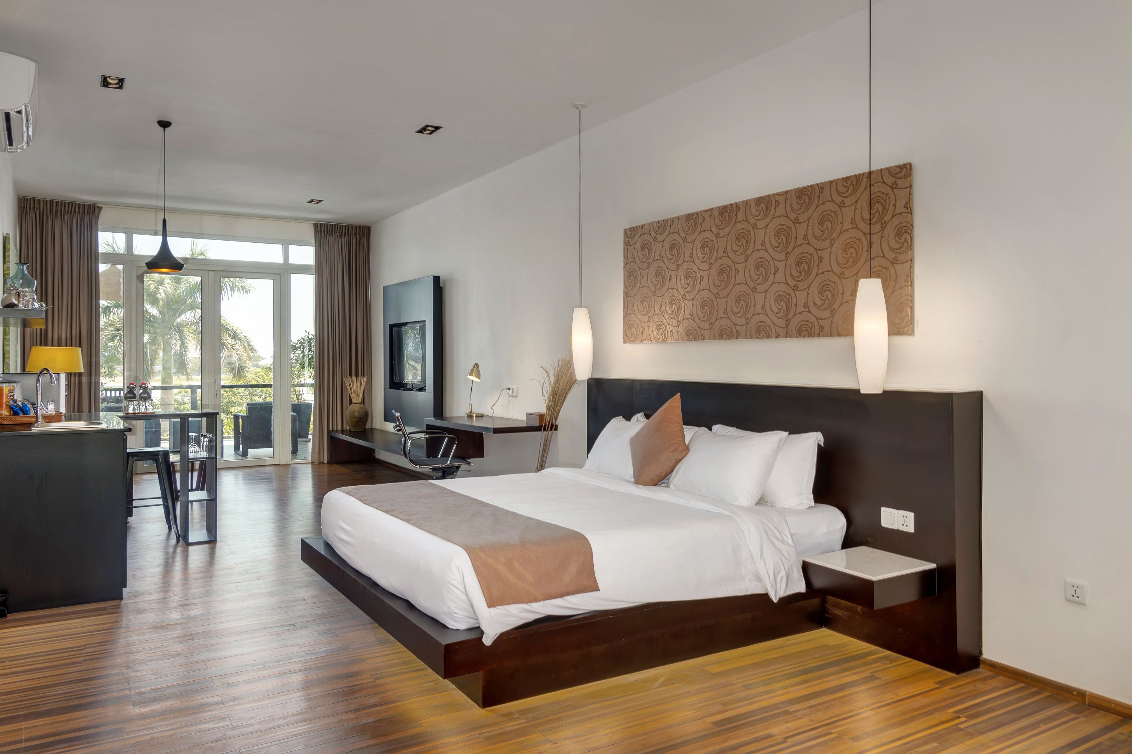 A modern hotel room with a large bed, a desk, and a television.