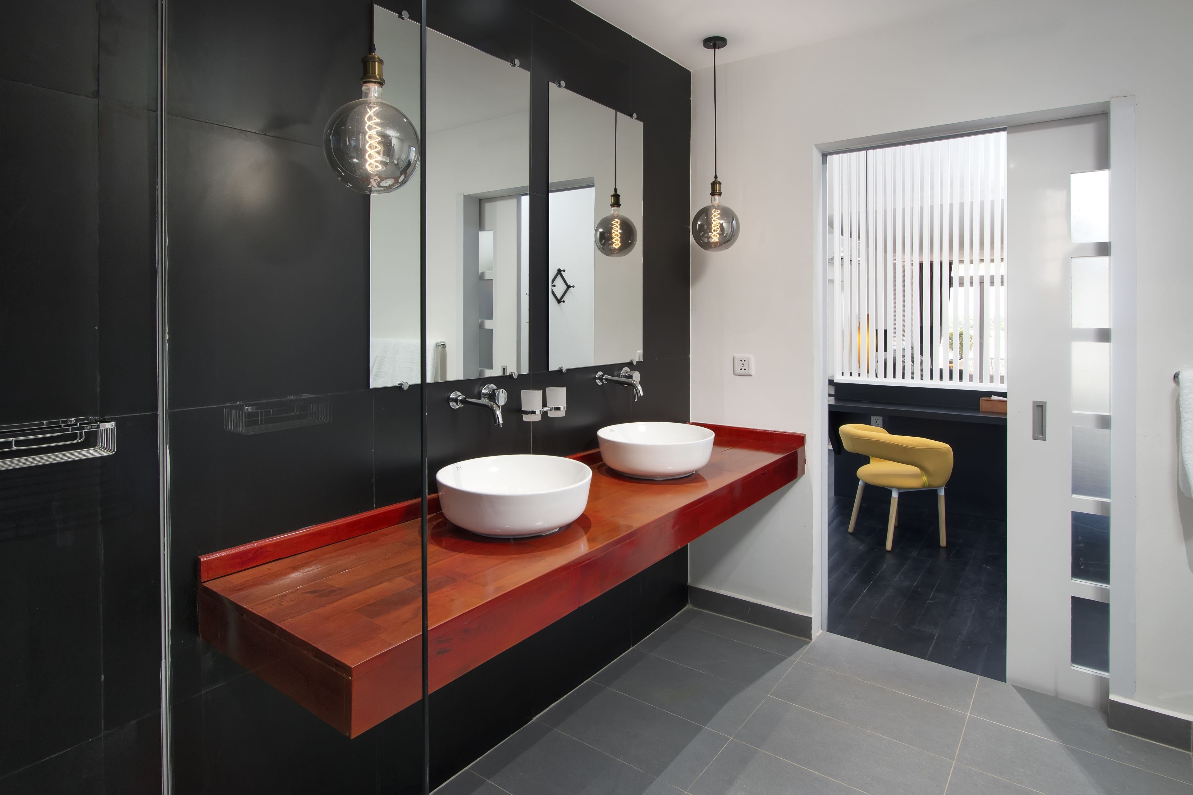 A modern bathroom with two white sinks, a large mirror, and a wooden vanity.