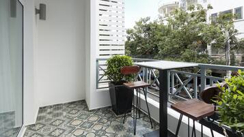 Ein Balkon mit gemusterten Fliesen, einem Blumentopf, einem Holztisch und einem Stuhl.