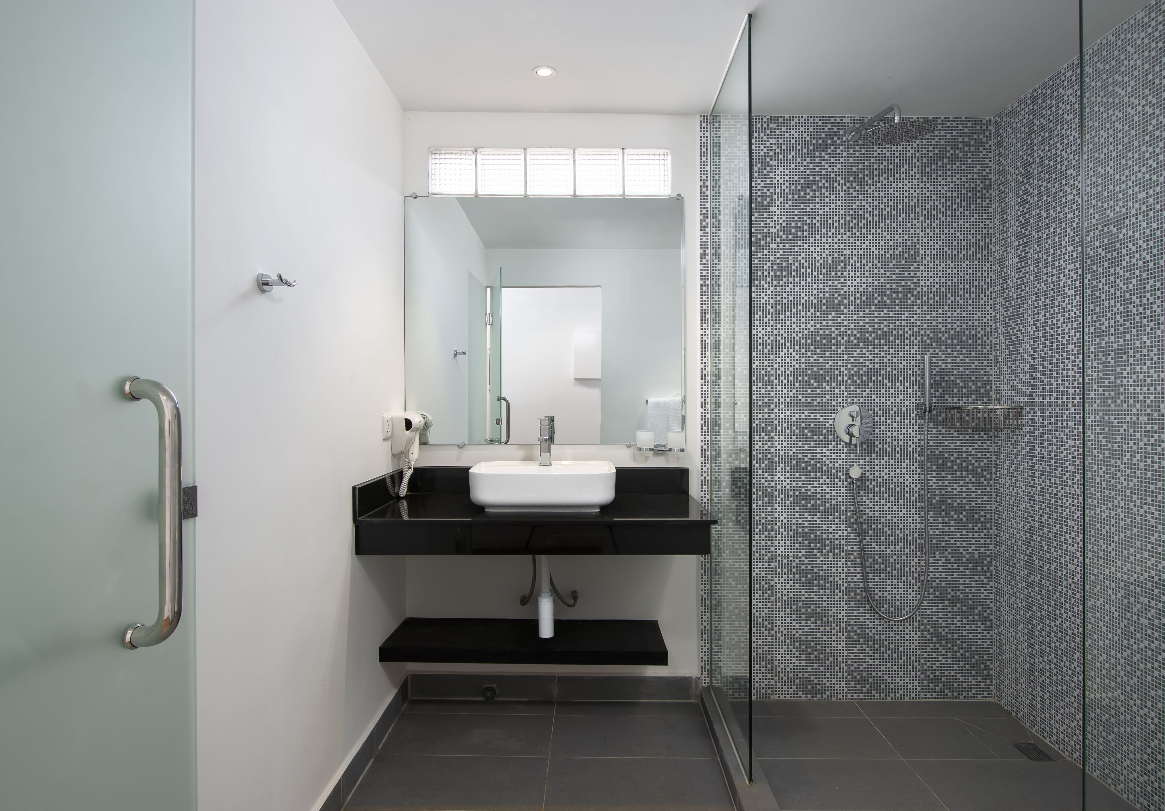 A modern bathroom with a glass shower enclosure, a white sink, and a black countertop.