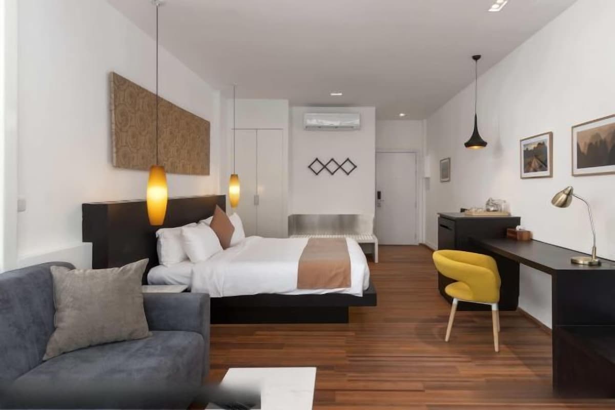 Een moderne hotelkamer met een bed, bureau, stoel en een bank.