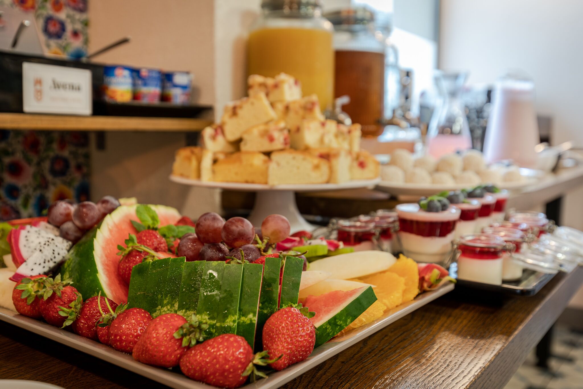 Una mesa de buffet con diversas frutas, postres y bebidas.