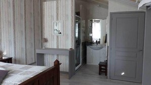 Un dormitorio con una cama, un tocador con espejo y una puerta.