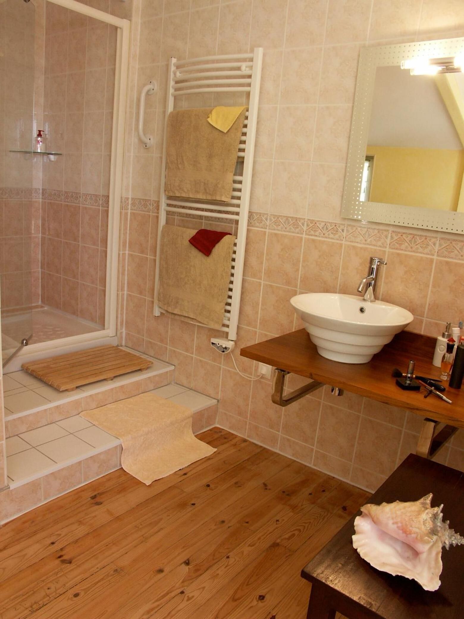 Ein Badezimmer mit Dusche, Waschbecken, Spiegel und Holzboden.