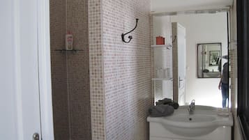 A bathroom with a shower, a sink, and a mirror.