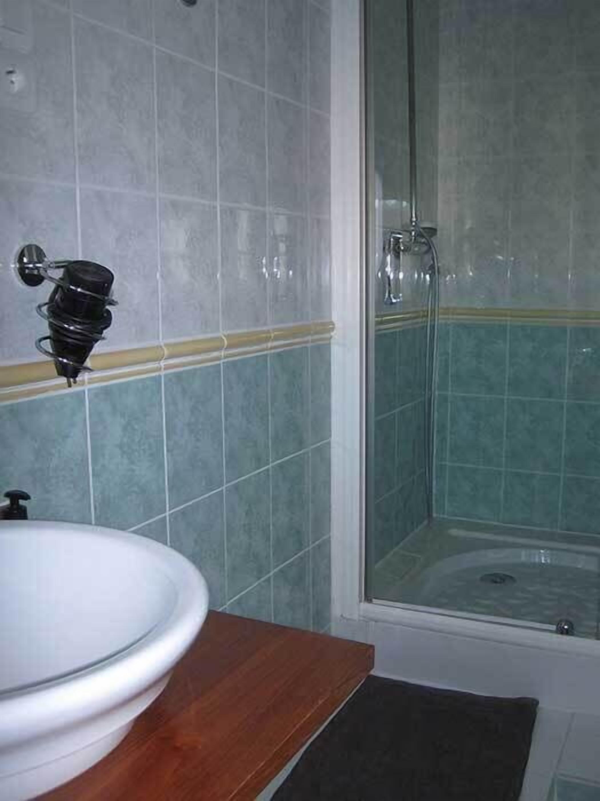 Un baño con lavamanos, espejo y ducha.