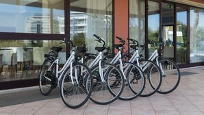 Une rangée de vélos est garée devant un bâtiment doté de grandes fenêtres et d’un sol carrelé.