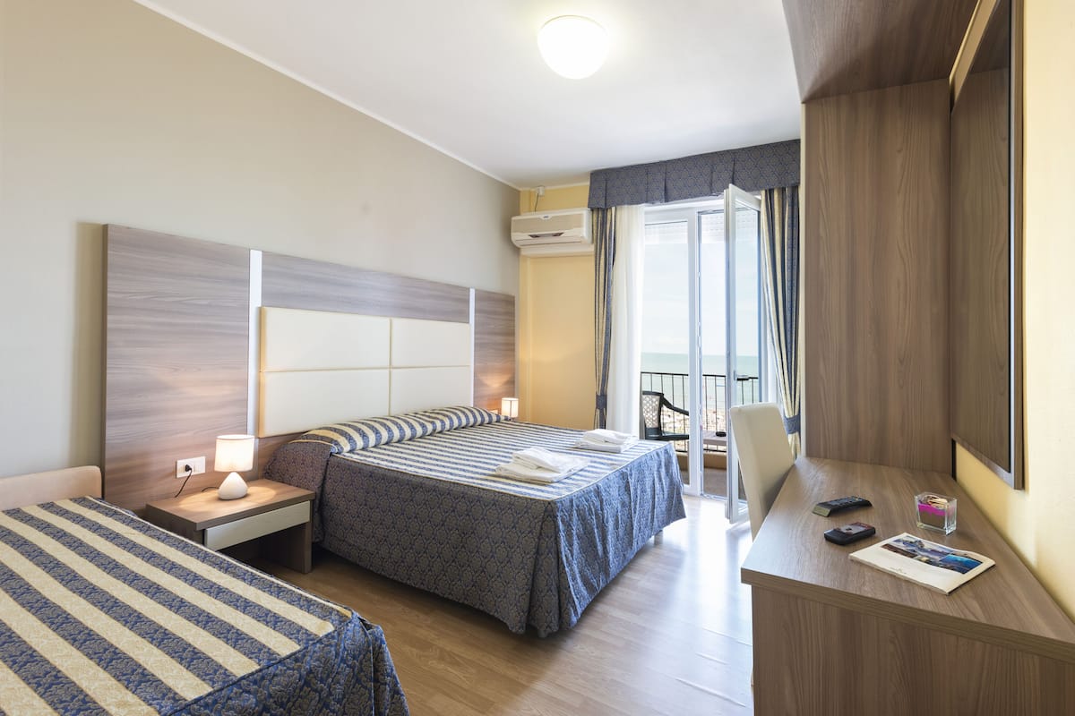 Una habitación de hotel con una cama, mesitas de noche, un escritorio y una silla.