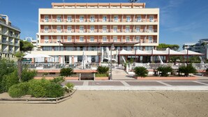 Un hôtel à plusieurs étages doté de balcons, d’un espace extérieur aménagé et offrant une vue sur la plage.