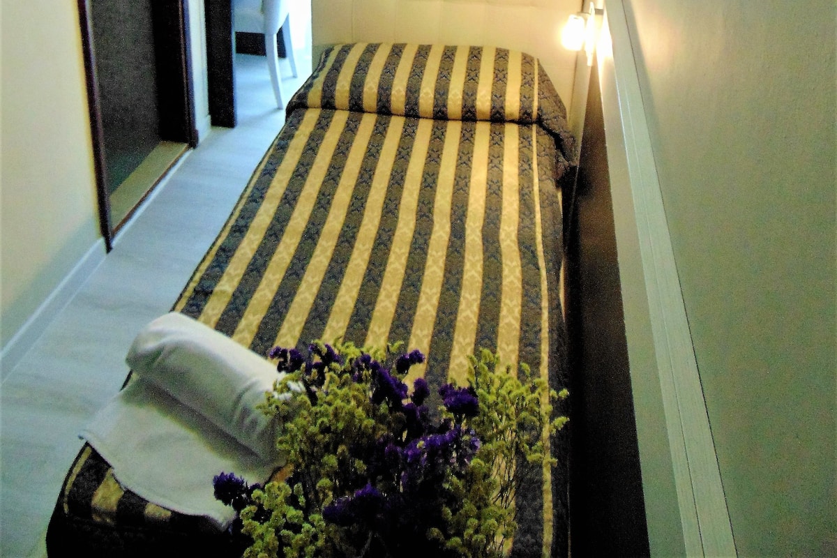 Un dormitorio pequeño y ordenado con cama, una silla y un escritorio.