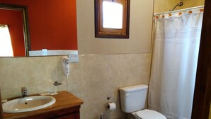 A bathroom with a sink, a bidet, a toilet, and a shower curtain. - Alquimia Cabañas Apart (El Bolson)