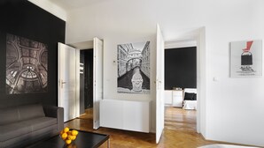 Una sala de estar moderna con un sofá gris, una mesa de centro con naranjas y un pasillo que conduce a una cocina.