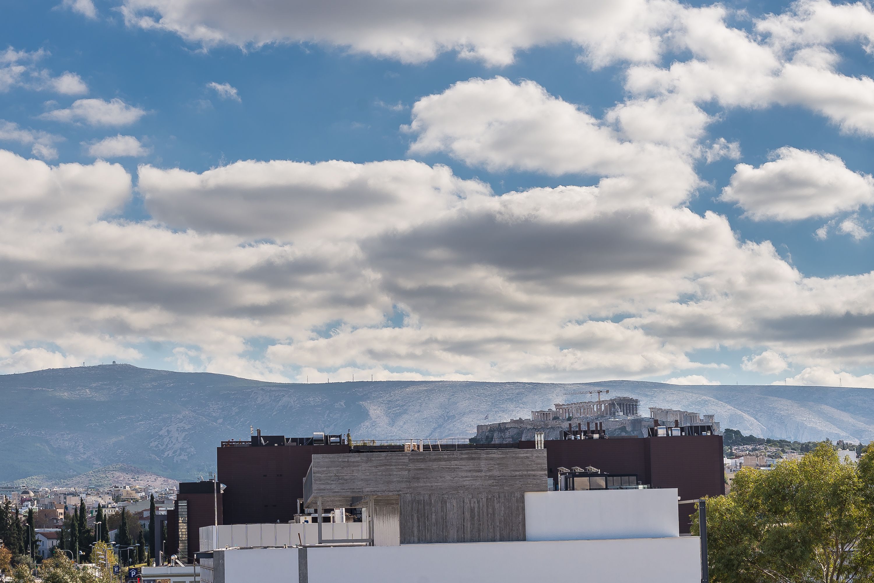 A cityscape with modern buildings and a mountain in the background.