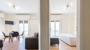A modern apartment with a dining area, a sofa, a bed, and a TV.