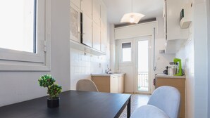A kitchen with white cabinets, a dark wooden table, and a potted plant.