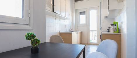 Una cocina con armarios blancos, una mesa de madera oscura y una planta en maceta.
