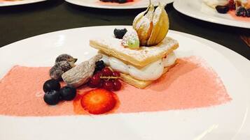 A dessert plate with a layered pastry, berries, and a dusting of powdered sugar.