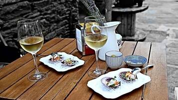 Una mesa de madera con dos copas de vino, una jarra y platos con comida.