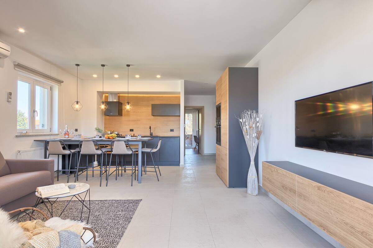 Ein modernes Wohnzimmer mit einer Couch, einem Couchtisch und einem an der Wand montierten Fernseher.